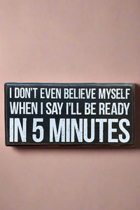 A black rectangle sign that says “I don’t even believe myself when I say I’ll be ready in 5 minutes” in white.