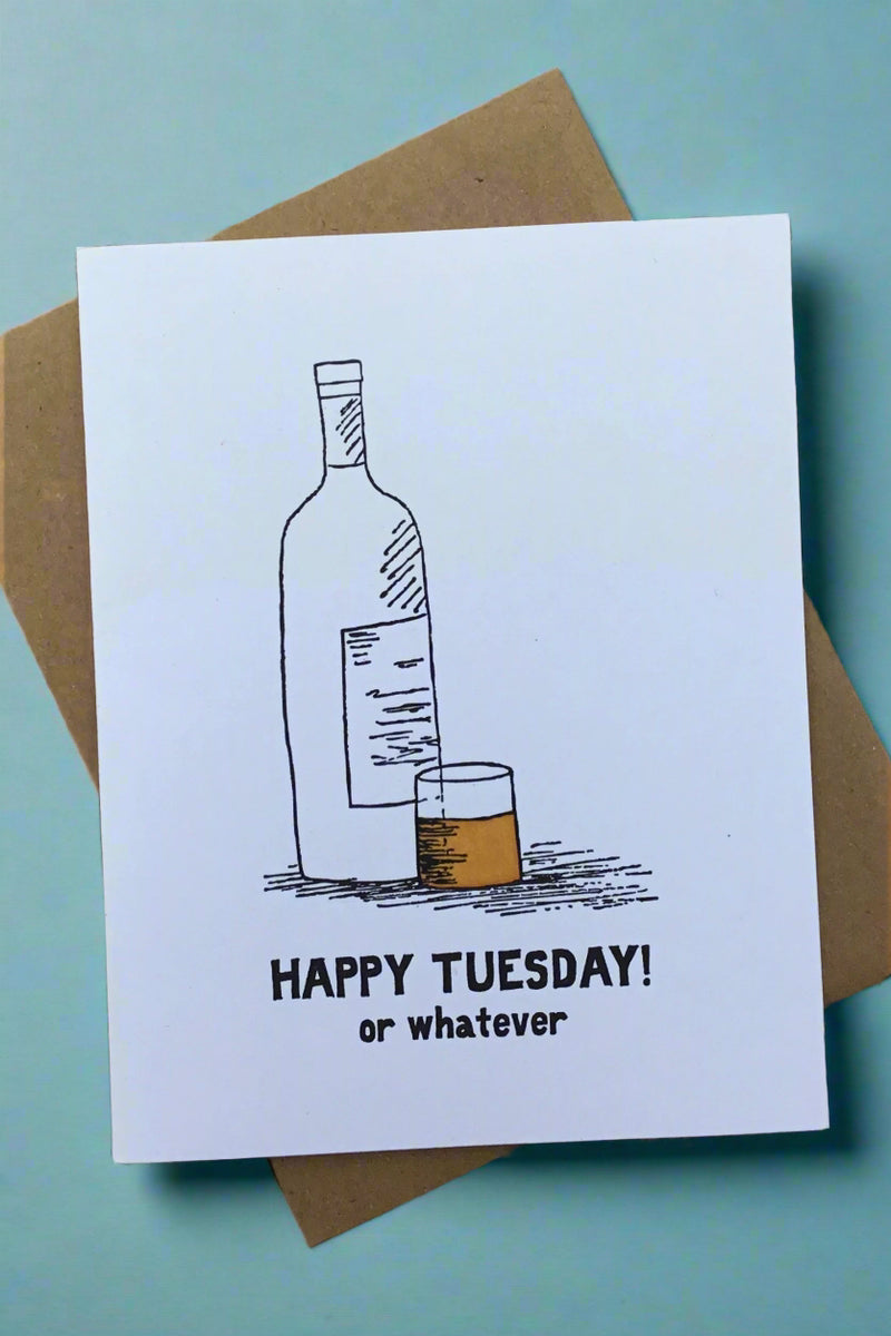 A white greeting card with an illustration of a bottle next to a glas with brown liquid in it and black text underneath that reads ‘Happy Tuesday! Or whatever.’