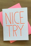 A solid white greeting card with large hot pink text that reads ‘Nice Try’ and matching hot pink envelope.