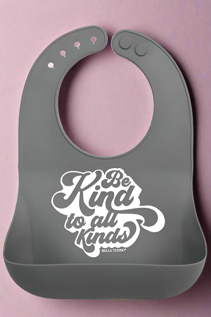 A grey adjustable neck bib with a the phrase Be Kind To All Kinds. Recommended for kids 6 months+.