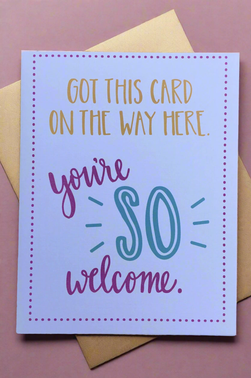 A white greeting card with a small polka dot boarder and text that reads ‘Got this card on the way here. You’re so welcome.’