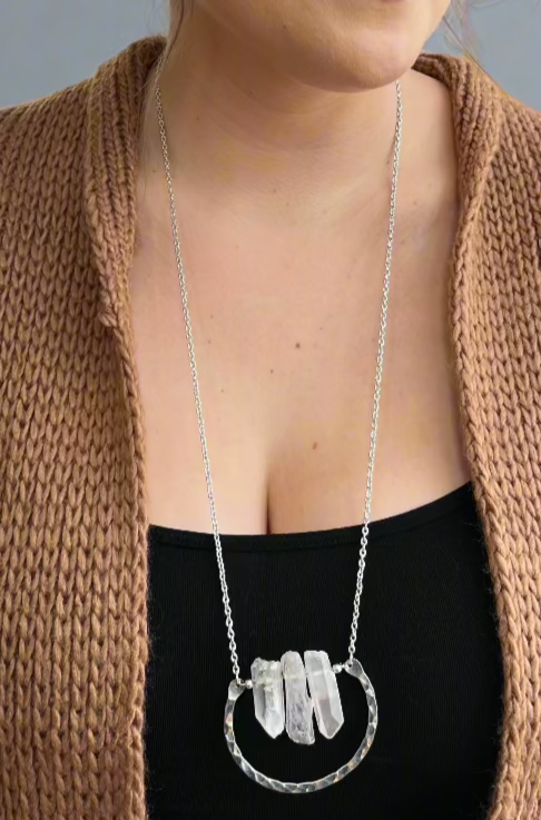 A long silver necklace featuring 3 clear quartz stones and a horseshoe shape.