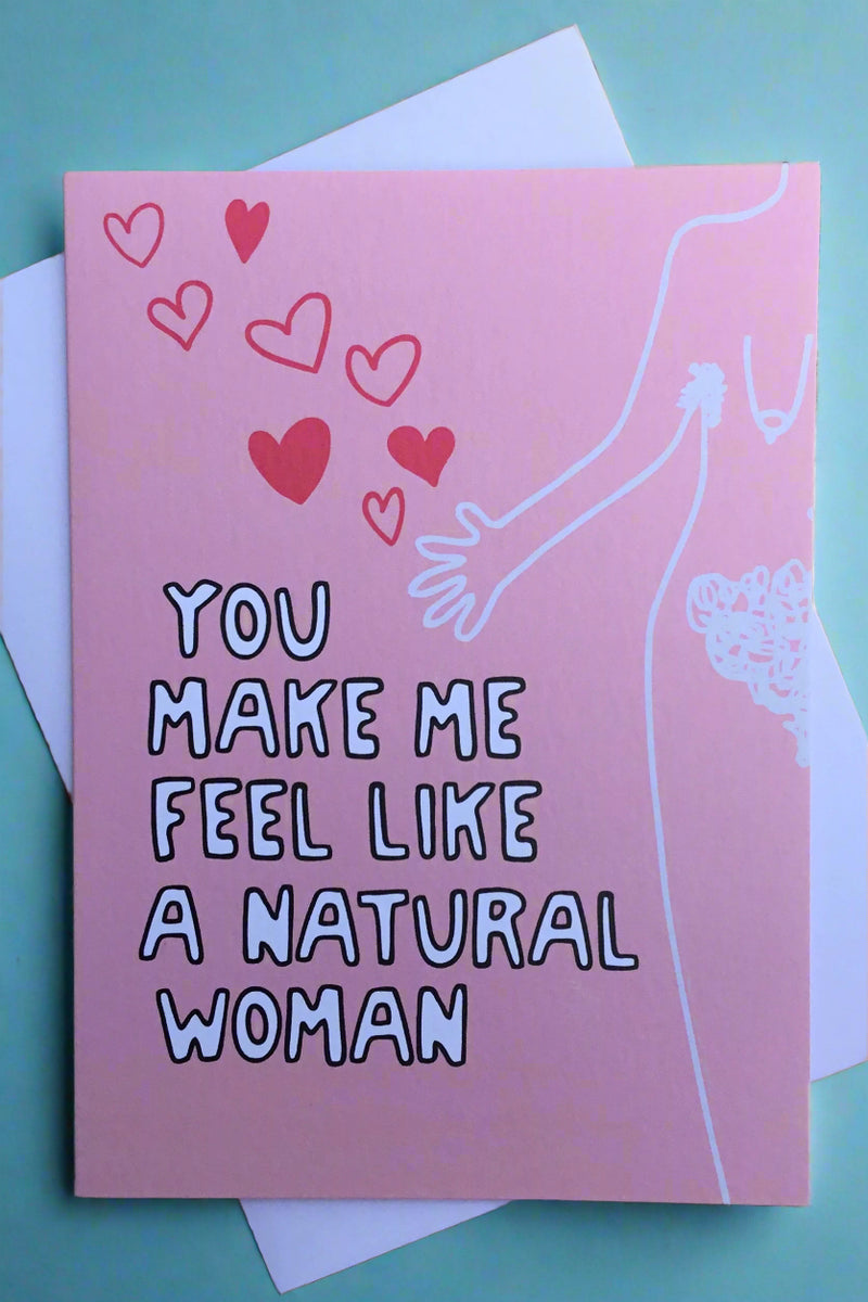A pink card with an image of a natural woman’s body, hearts, and says “You make me feel like a natural woman.“
