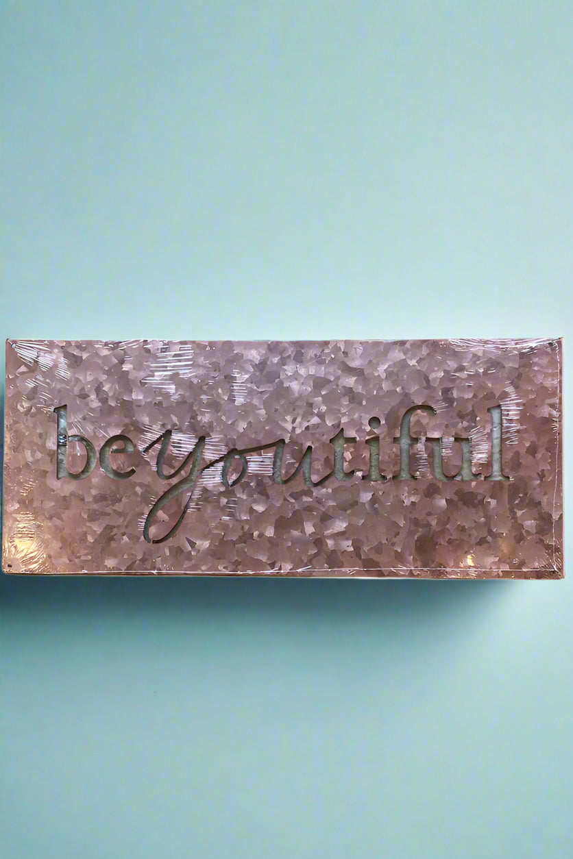 A rectangular sign in light pink hammered tin with ‘BeYOUtiful’ cut out.