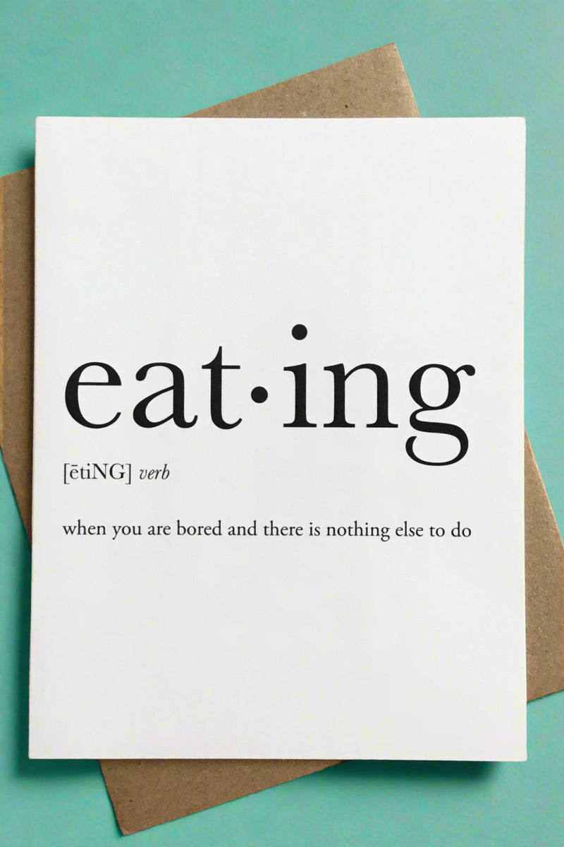 A simple white greeting card with black text that reads ‘eating - [ētiNG] verb - when you are bored and there is nothing else to do’.