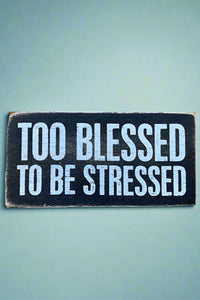 A black rectangle sign that says “Too blessed to be stressed” in white.