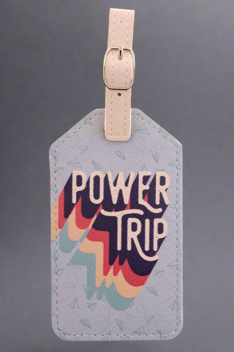 A grey, vegan leather luggage tag that says “Power Trip” on it.