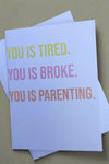 White minimalist greeting card with text that reads ‘You Is Tired. You Is Broke. You Is Parenting.’ and white envelope.