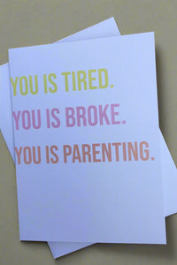 White minimalist greeting card with text that reads ‘You Is Tired. You Is Broke. You Is Parenting.’ and white envelope.