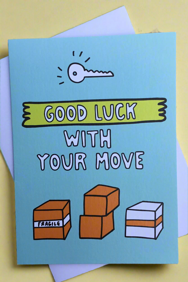 A light blue greeting card with images of moving boxes and a key with text that reads ‘Good Luck With Your Move’.
