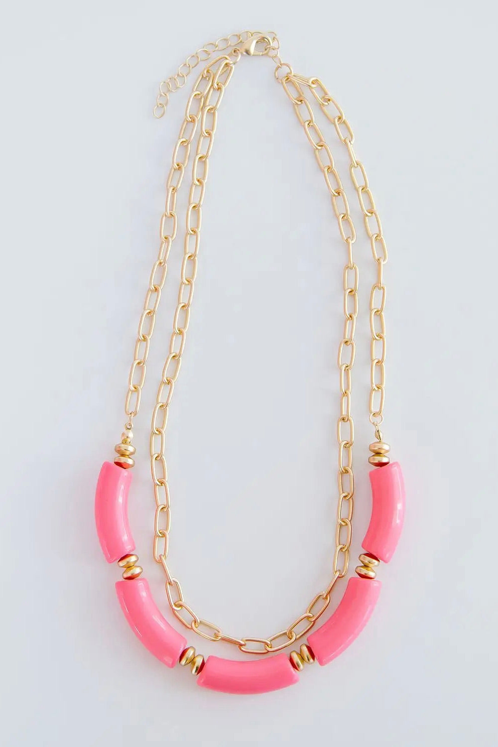 The Holly necklace is layered with a shorter, chain link pattern while the longer chain is strung with several pink, elongated beads.