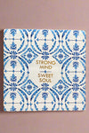 A small square sign with a white and blue pattern and says “Strong mind, sweet soul” written in gold.