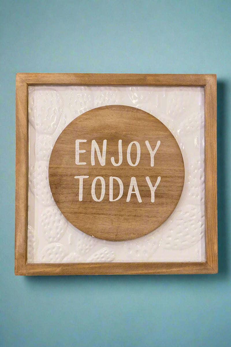 A brown and white sign that says “Enjoy Today” in the middle of a wood circle.