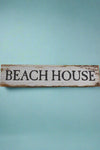 A aged white wood sign that says Beach House on the front.