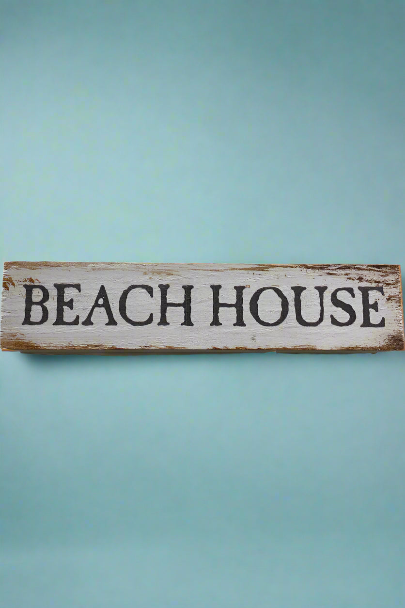 A aged white wood sign that says Beach House on the front.