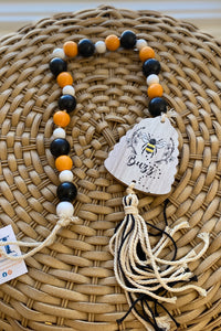 Black, white and orange wooden bead garland with a beehive shaped ornament and tassel at the end.