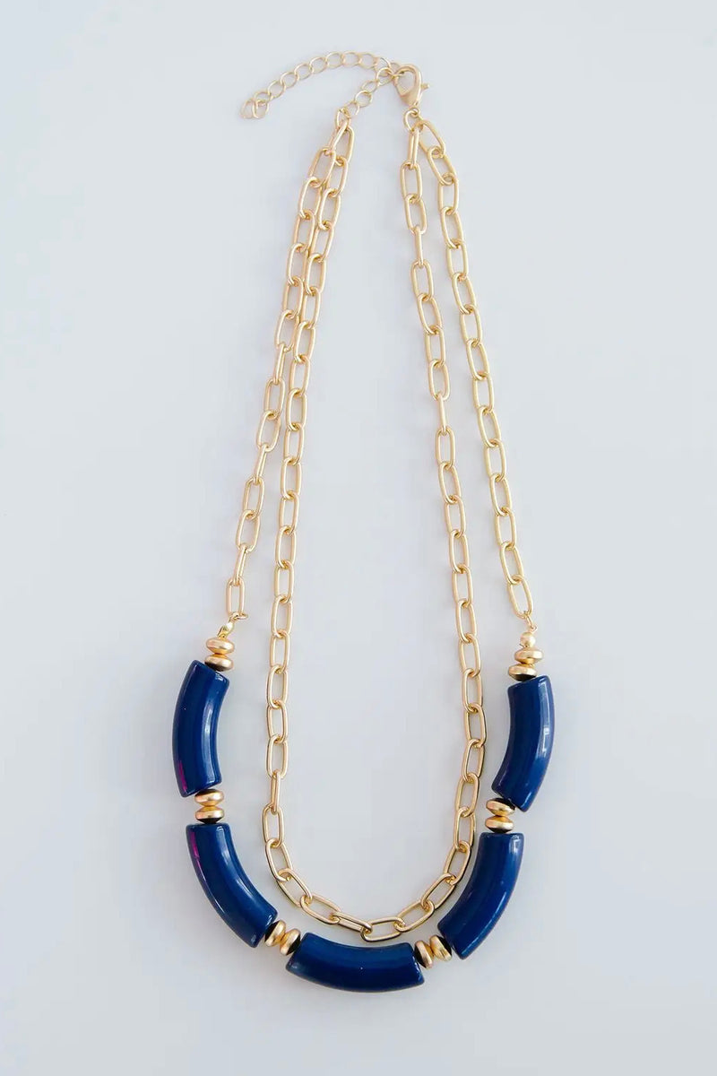 The Holly necklace is layered with a shorter, chain link pattern while the longer chain is strung with several royal blue, elongated beads.