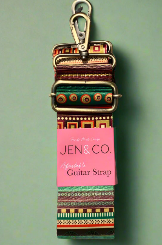 An adjustable purse strap made from guitar straps. Has a colorful design and gold accents.