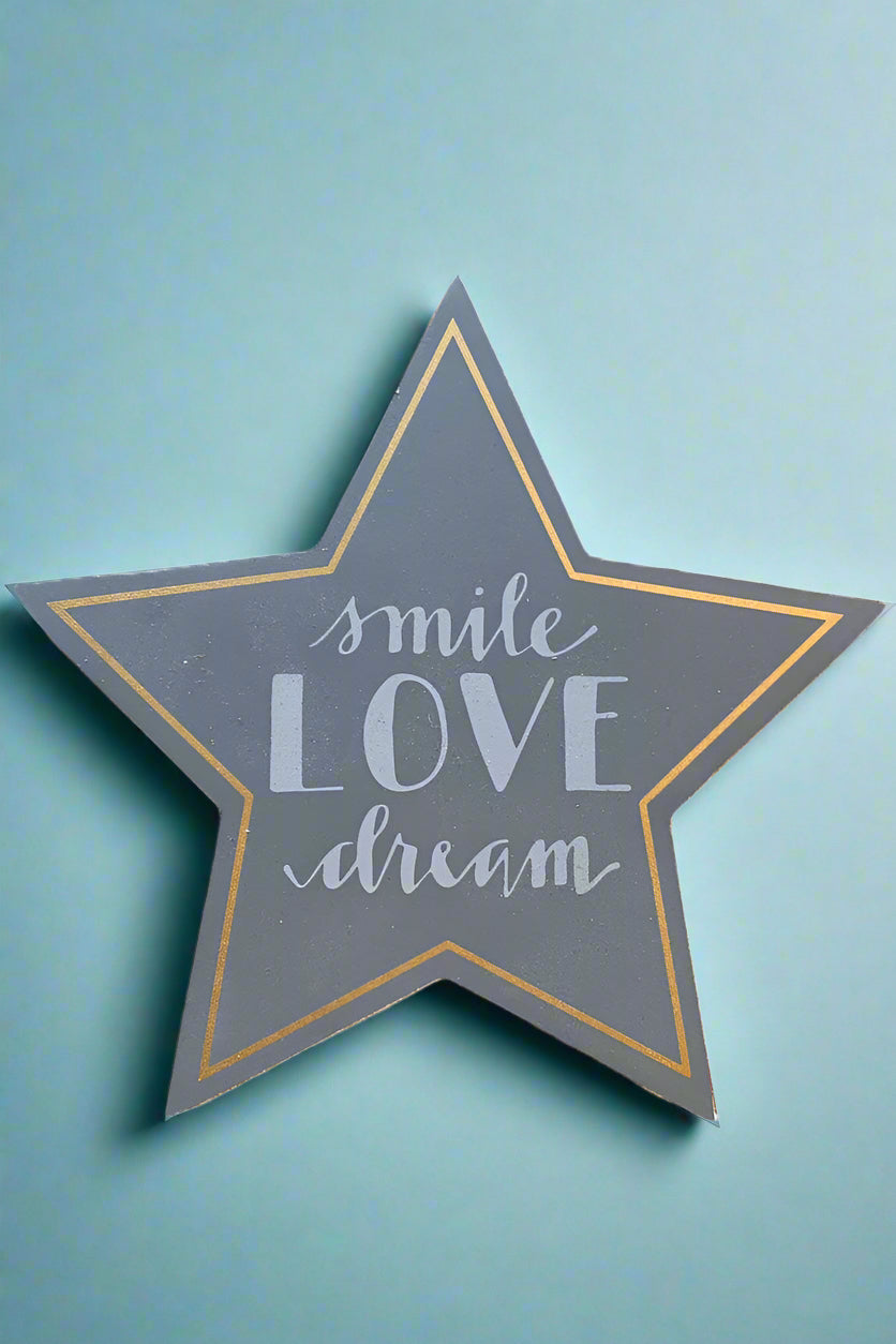 A dark grey star shaped sign that says “Smile, love, dream.”