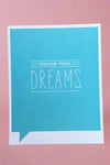 A greeting card with bright blue background and white text that reads ‘Follow your Dreams.’