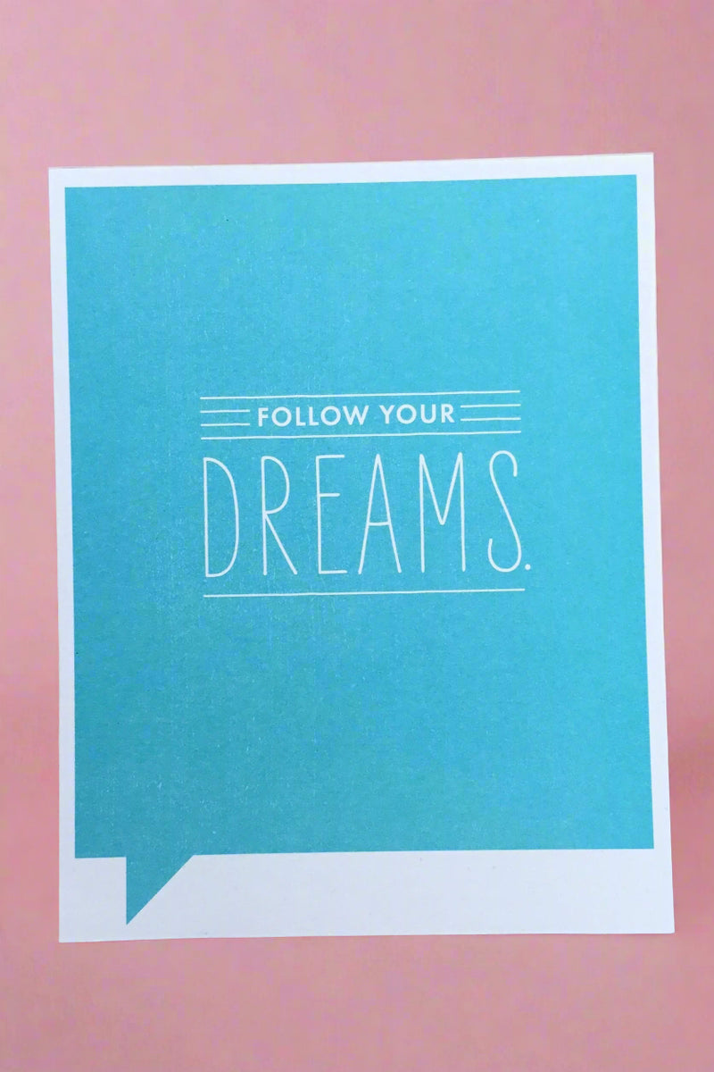 A greeting card with bright blue background and white text that reads ‘Follow your Dreams.’