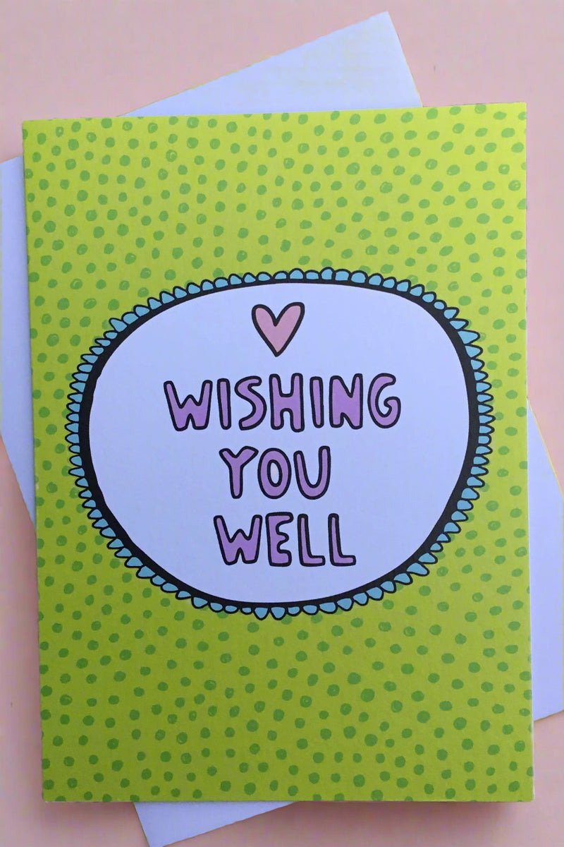 A greeting card that says “Wishing You Well” in purple with a green polka dot background.