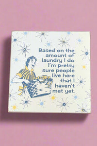 4 inch solid wood block sign with quirky retro print and quote that reads, “Based on the amount of laundry I do I’m pretty sure people live here that I haven’t met yet.”