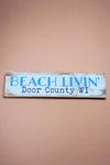 A horizontal rectangle sign in rustic white that says “Beach Livin’ Door County Wi.”