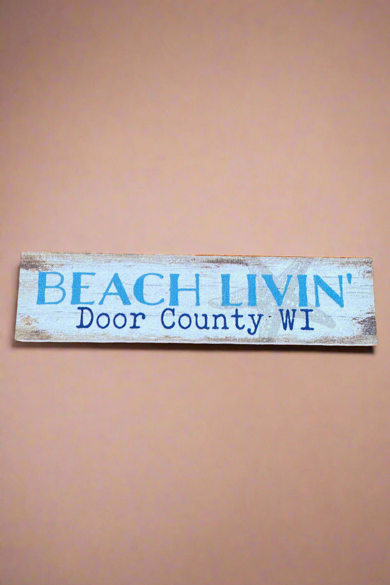 A horizontal rectangle sign in rustic white that says “Beach Livin’ Door County Wi.”