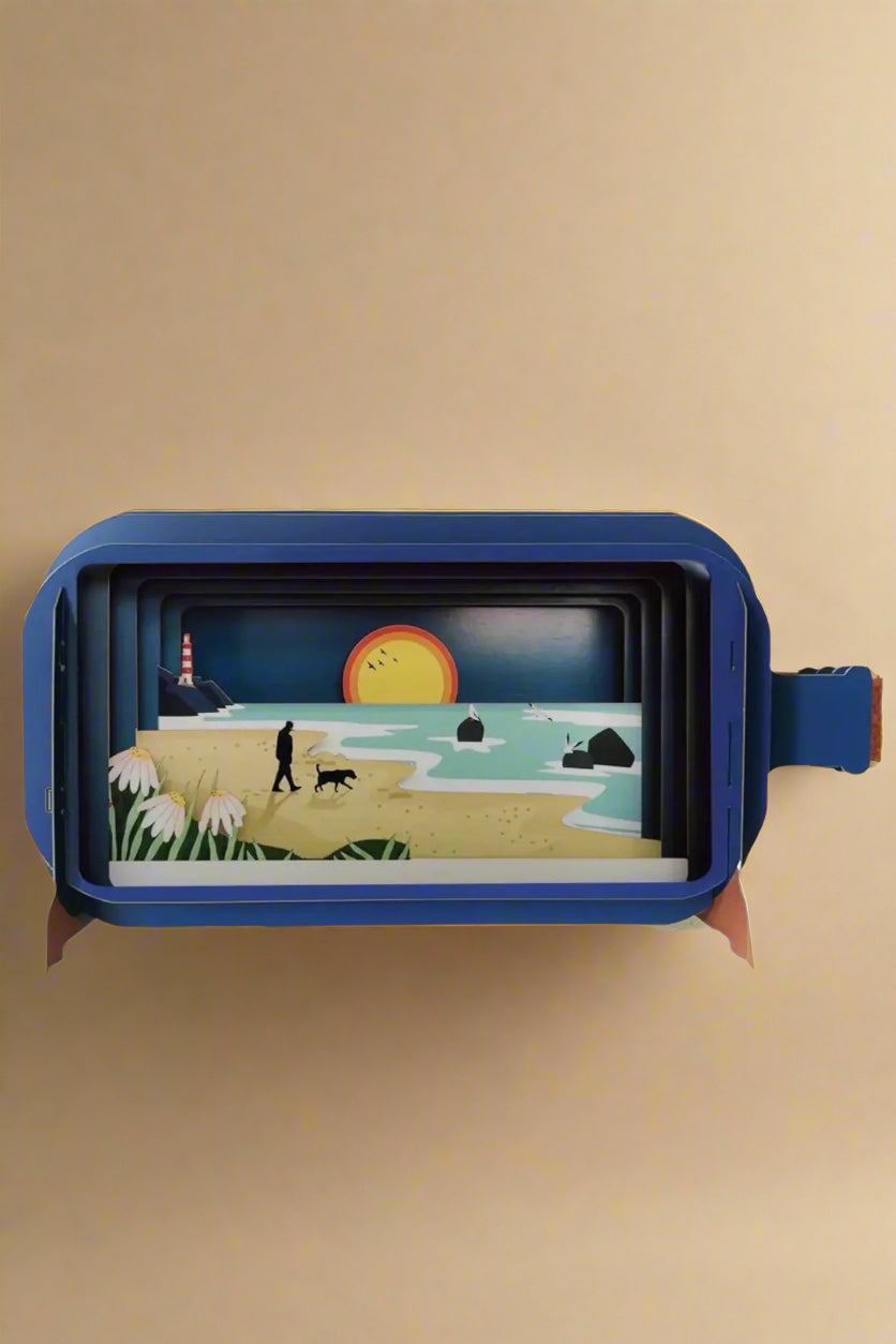 A 3D greeting card in the shape of a corked bottle with beach scene inside.