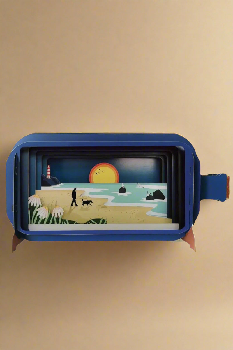 A 3D greeting card in the shape of a corked bottle with beach scene inside.