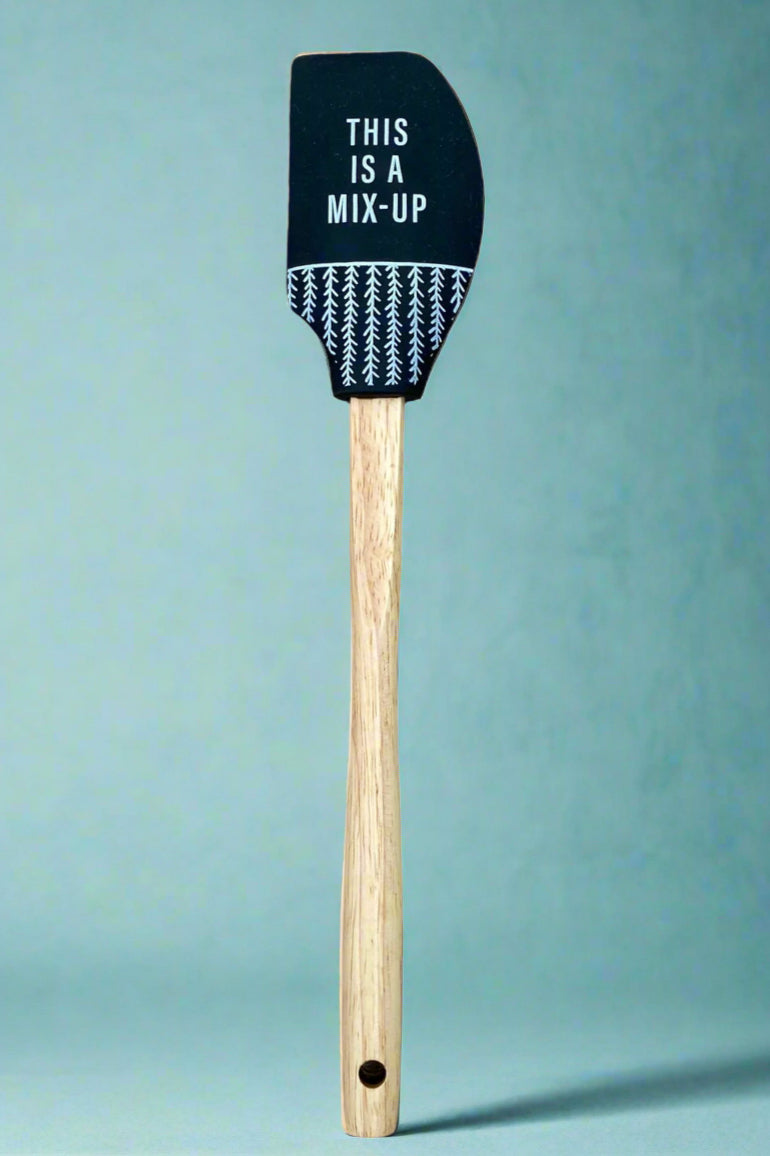 A silicone spatula that says ‘This is a mix-up” with wood handle.