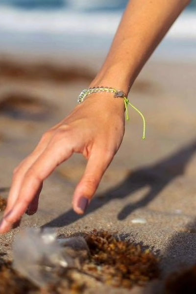 An adjustable lime green bracelet with clear beads and a sea turtle charm.