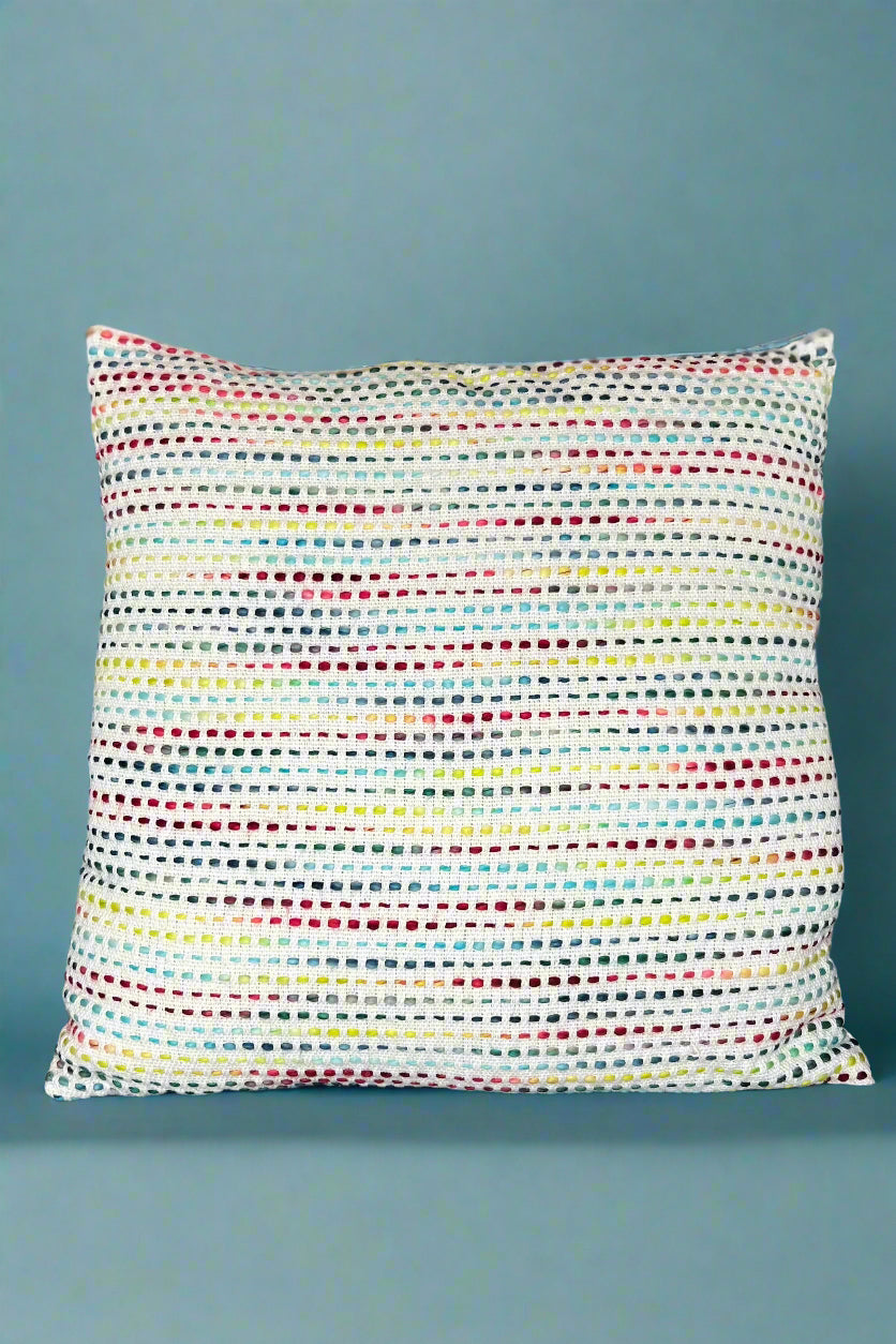 A square accent pillow with exposed multicolored stitching.